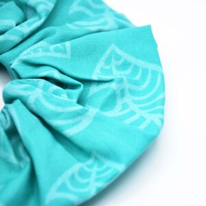 May include: A turquoise scrunchie with a white leaf pattern.