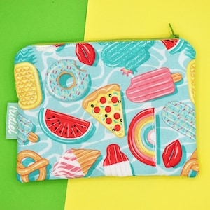 Può includere: Una pochette blu con cerniera con una stampa colorata a tema estivo. La stampa presenta una fetta di anguria, una ciambella, una fetta di pizza, un galleggiante arcobaleno, un ghiacciolo, un pretzel e un cactus. La pochette ha una cerniera verde e il testo "tridiel" è stampato sul lato.