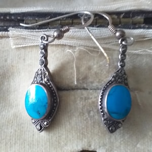 May include: A pair of silver earrings with turquoise stones and marcasite accents. The earrings are in a small box with a label that reads "Breet & Company Ltd Goldsmiths & Silversmiths 857 87 Hostgate Road Newcastle on Tyne."