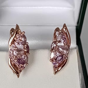 Peut inclure: Une paire de boucles d'oreilles en or rose ornée d'un groupe de pierres précieuses roses et violettes de taille marquise et ronde. La monture en métal présente un design incurvé en forme de feuille entourant les pierres facettées.