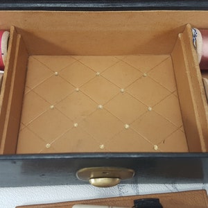 May include: An open black box with a gold latch. The box is lined with brown fabric and contains spools of thread in various colors, including pink, purple, red, yellow, and beige.