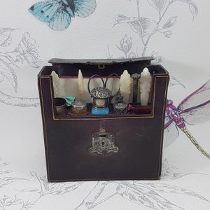 May include: A brown leather travel case with a silver lock and keyhole. The case is open and contains a variety of silver and bone tools, including a pair of scissors, a small bottle, and a bone-handled knife.