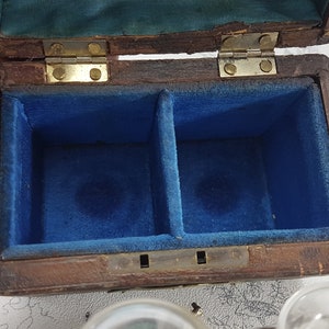 May include: A wooden box with a hinged lid, lined with blue velvet. The box has two compartments inside.