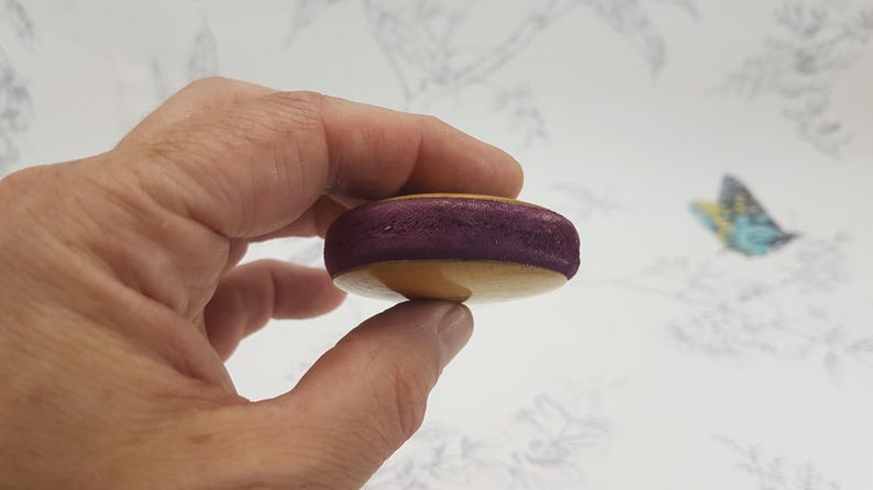 May include: A purple and beige macaron cookie held in a hand.