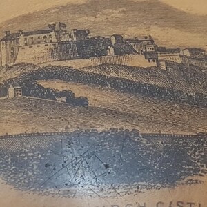 May include: A close-up of a wooden trinket box with a brown background and a black and white image of a castle on a hill. The text "EDINBURGH CASTLE" is printed at the bottom of the image.