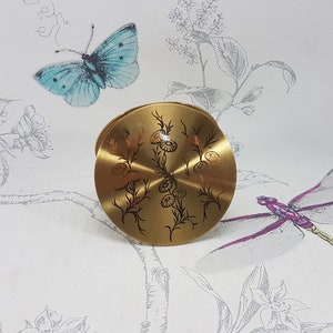 Vintage gold tone powder compact with etched floral decoration