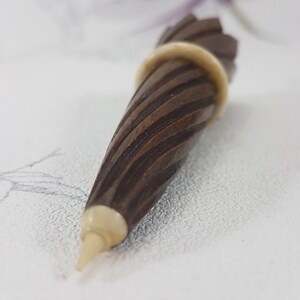 May include: A brown wooden pencil sharpener with a white tip and a spiral design.