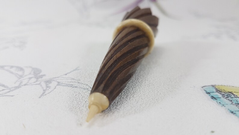 May include: A brown wooden pencil sharpener with a white tip and a spiral design.