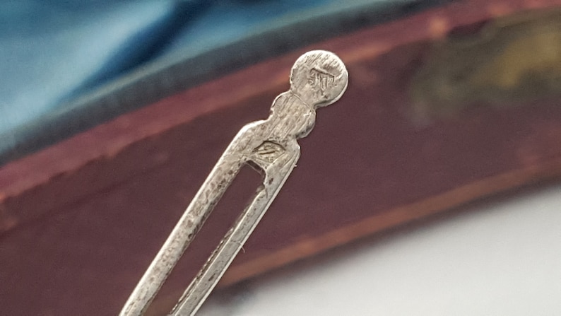 May include: Close-up of a silver metal hair clip with a circular marking that reads "925".