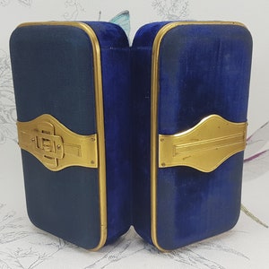 May include: A blue velvet jewelry box with gold accents and a hinged closure. The box is open and the interior is lined with blue velvet.