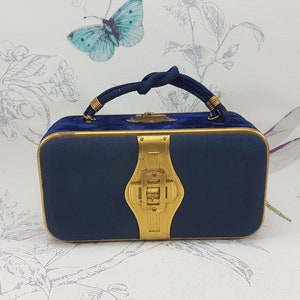 May include: A small, navy blue velvet handbag with a gold clasp and a knotted gold handle.