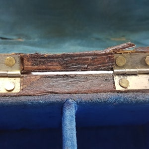 May include: A wooden box with a blue velvet interior and two compartments. The box has brass hinges and is slightly damaged.