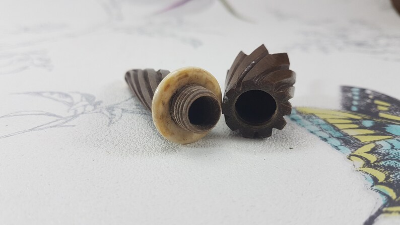 May include: Two vintage wooden thimbles with a spiral design. One thimble has a white plastic top with a threaded hole.