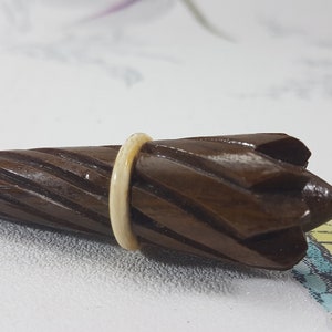 May include: A small, wooden, brown umbrella-shaped object with a white ring around the middle. The object is carved with a spiral pattern and has a pointed tip.