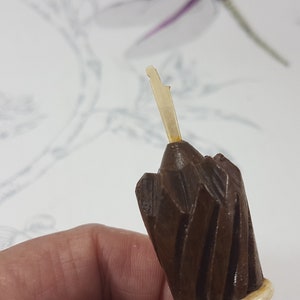May include: Close-up of a brown wooden pencil sharpener with a white plastic blade. The sharpener has a spiral design and a pointed tip.