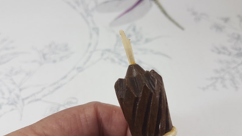 May include: Close-up of a brown wooden pencil sharpener with a white plastic blade. The sharpener has a spiral design and a pointed tip.