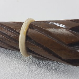 May include: A wooden, brown, spiral-shaped umbrella handle with a white ring around the top.