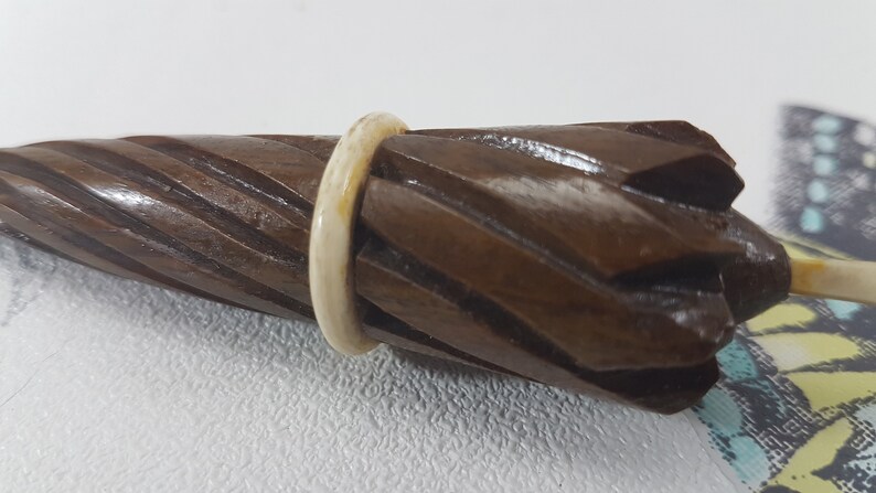 May include: A wooden, brown, spiral-shaped umbrella handle with a white ring around the top.