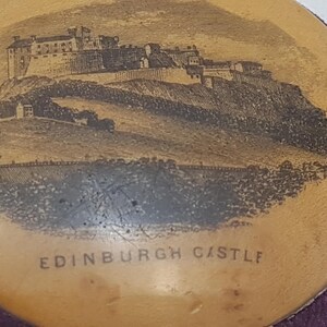 May include: A round, wooden trinket box with a purple velvet lining. The lid features a black and white image of Edinburgh Castle with the text "EDINBURGH CASTLE" printed below the image.