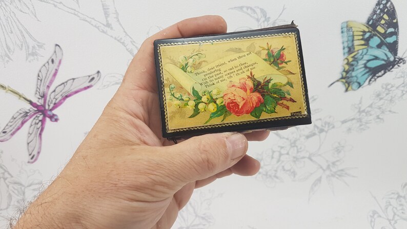 May include: A small, black, rectangular box with a gold floral design and a scroll with the text "Think, dear friend, when thou art wandering, as I am, and to thee, in this path, so red to thine, With the same hopes and changes, Think of me as I think of thee."
