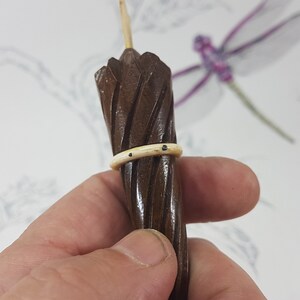 May include: A small, wooden, brown umbrella with a white band around the middle. The umbrella is held in a hand.