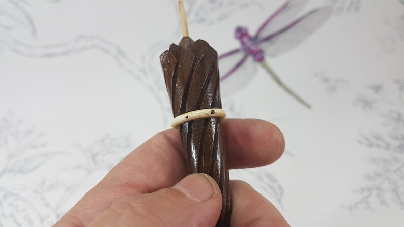 May include: A small, wooden, brown umbrella with a white band around the middle. The umbrella is held in a hand.