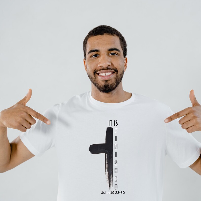 Peut inclure: Un t-shirt blanc avec une croix noire et le texte "IT IS FINISHED" verticalement sur le c&ocirc;t&eacute; droit de la croix. Le texte "John 19:28-30" est imprim&eacute; sous la croix.