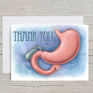 May include: A greeting card with a pink illustration of a stomach and connected organs. The words "THANK YOU" are printed in teal above the illustration. The background is a light blue watercolor wash.