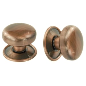 May include: Two antique-style cabinet knobs with a copper finish. The knobs have a rounded shape with a circular base and a slightly domed top. The finish has a mottled appearance, with variations in colour.