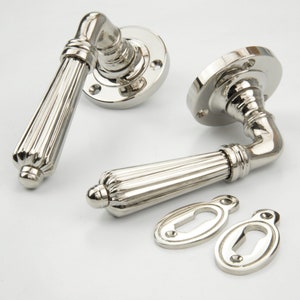 May include: Two polished nickel door handles with a fluted design and matching keyhole covers. The handles are designed for interior doors.