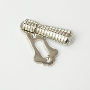 May include: A silver-toned keyhole cover with a decorative, ribbed knob. The knob is attached to the cover with a hinge.