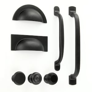 May include: A set of black cabinet hardware, including knobs, pulls, and cup pulls. The hardware is made of metal and has a matte black finish.