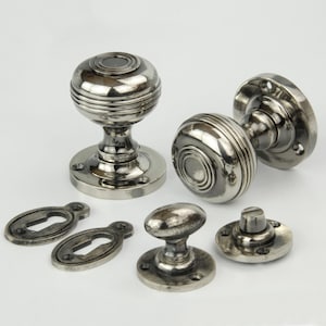 May include: Set of antique silver door knobs with keyhole escutcheons and a round knob for a cabinet door.