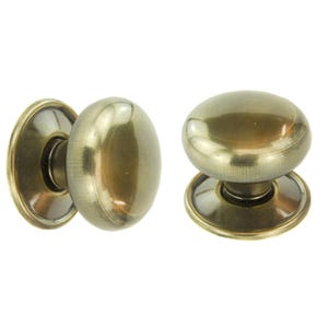 May include: Two antique brass cabinet knobs. The knobs have an oval shape and a circular base. The finish is a warm, aged brass colour, suggesting a vintage or classic style. The knobs are designed for furniture or cabinetry.