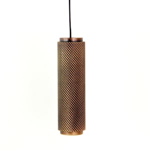 May include: A bronze-coloured, cylindrical pendant light fitting with a textured, diamond-patterned surface. The light hangs from a black cord against a white background. The fitting has a simple, modern design.