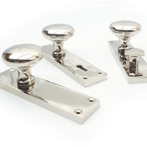 May include: Polished chrome door furniture set. The set includes three door knobs with oval handles and rectangular backplates. The hardware is designed for interior doors and has a shiny, reflective surface.