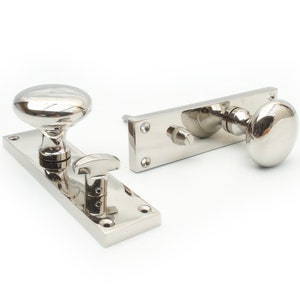 May include: A pair of polished nickel door knobs with a square backplate and a lever handle. The knobs are round and have a smooth, shiny finish.