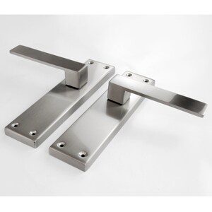 May include: Two brushed nickel door handles with square backplates and rectangular levers.