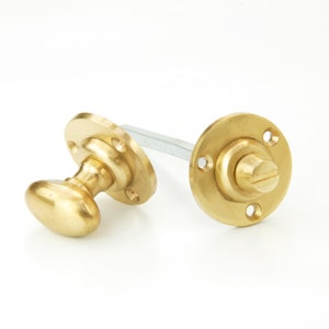 May include: A pair of polished brass door knobs with a round base and an oval-shaped handle. The knobs are connected by a metal rod.