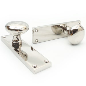 May include: Two polished nickel door handles with round knobs. The handles are rectangular and have a smooth, shiny finish.