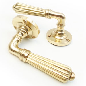 May include: A pair of polished brass door handles with a fluted design. The handles have a traditional style and are suitable for interior doors.