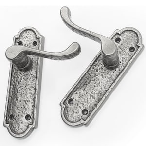 May include: Two silver door handles with a hammered finish and a curved lever design. The handles have a rectangular backplate with a decorative edge.