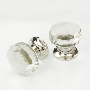 May include: Two clear glass door knobs with faceted edges and polished chrome bases.