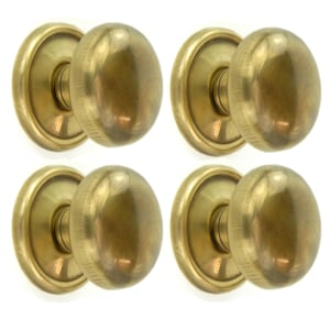May include: Four antique brass door knobs. Each knob features an oval shape and a circular backplate. The brass has a warm, aged patina. The knobs are arranged in a square formation against a white background.