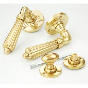May include: A set of polished brass door handles with a fluted design. The handles are shown with their matching backplates and a knob.