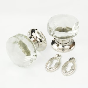 May include: Pair of clear glass door knobs with polished nickel finish and keyhole escutcheons.
