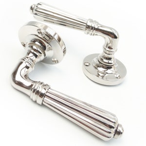 May include: A pair of polished nickel door handles with a fluted design. The handles have a traditional style and are suitable for interior doors.