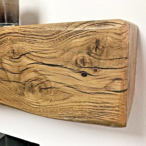 May include: A rustic wooden shelf with a natural wood finish and a slightly curved edge. The shelf has a knotty grain pattern and a warm brown color.