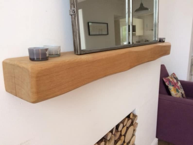 May include: A natural wood floating shelf with a live edge, mounted on a white wall. Two small glass candle holders sit on the shelf, and a rectangular mirror is mounted above. The shelf is approximately 60 inches long.