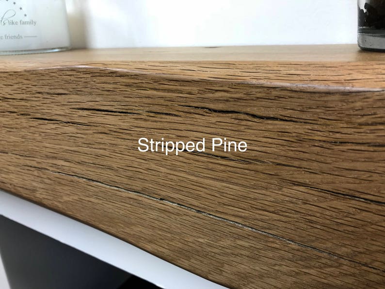 May include: Close-up of a section of a wooden shelf with the text "Stripped Pine" in white. The wood has a natural, textured grain and a warm, brown color. The shelf appears to be part of a larger piece of furniture.